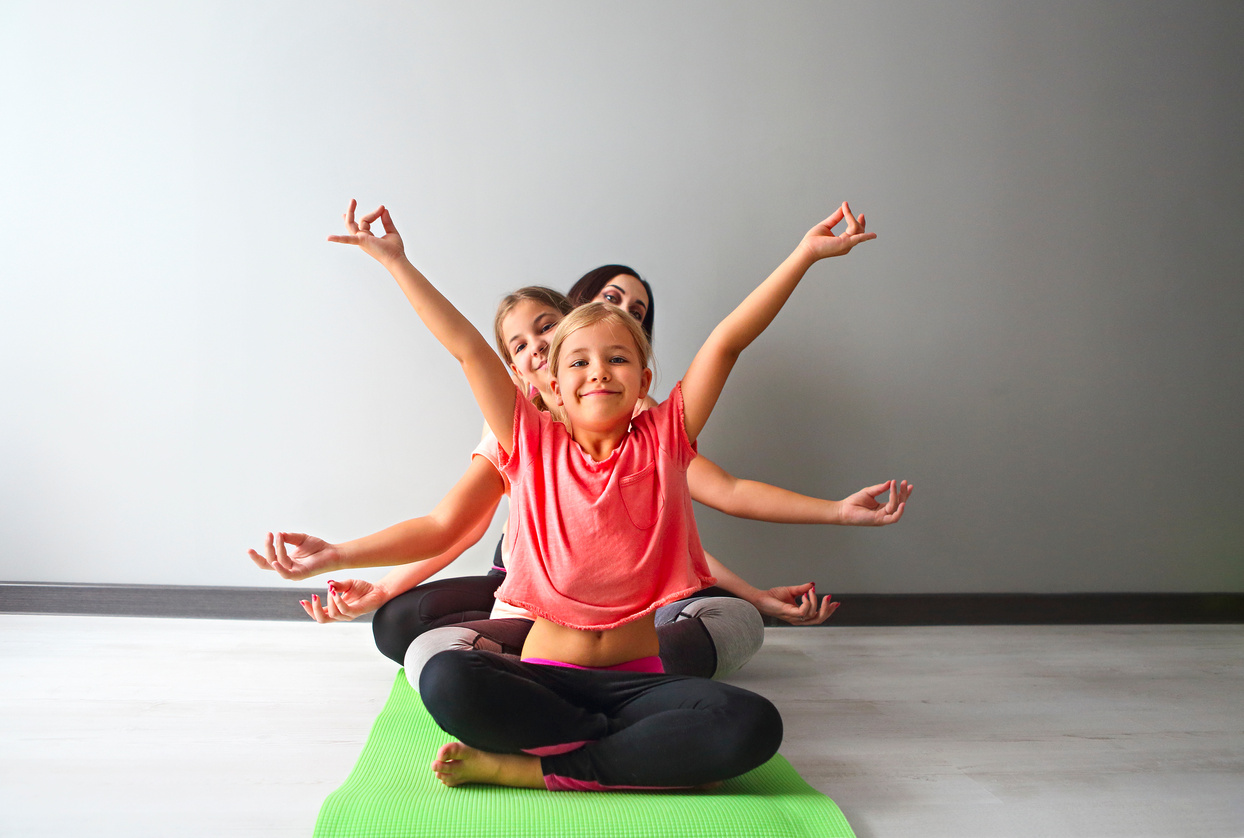 Young woman having fun with kids doing yoga